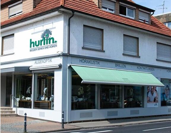 Optiker- und Hörakustik-Geschäft mit Schaufenstern, Brillen und Kontaktlinsen im Angebot.